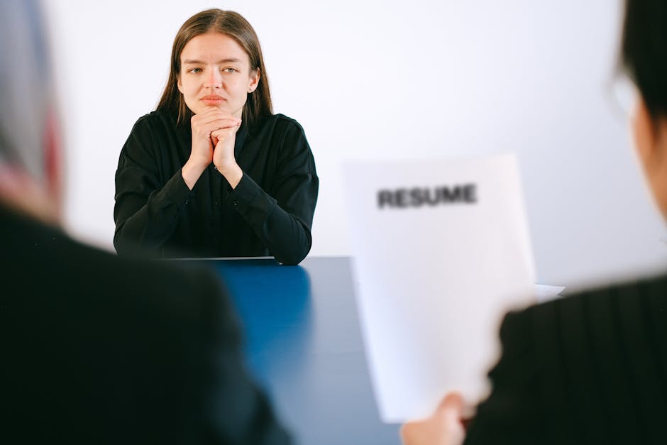 A woman in a job interview facing two employers with a focus on her resume